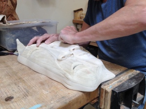 A student refines the surface of a sculptural mask in the wood shop at UNM Taos.